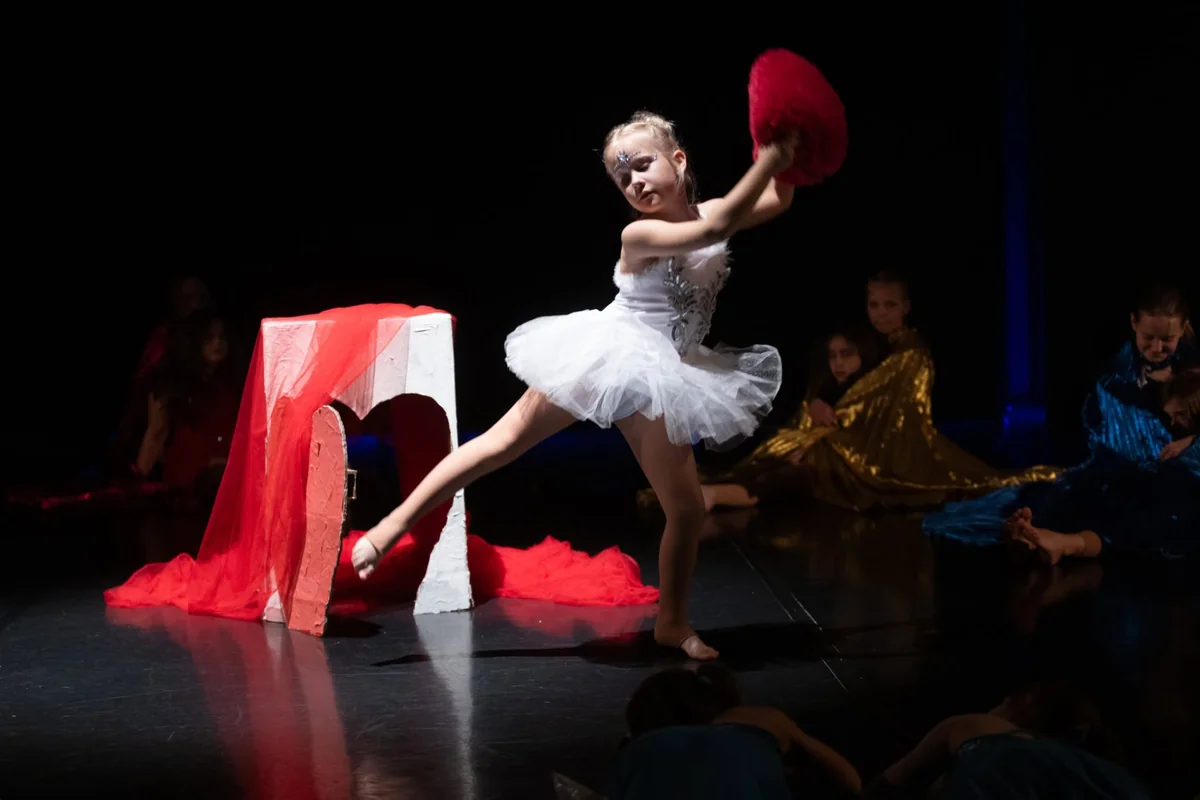 Mala baletka v beli tutu med nastopom na odru